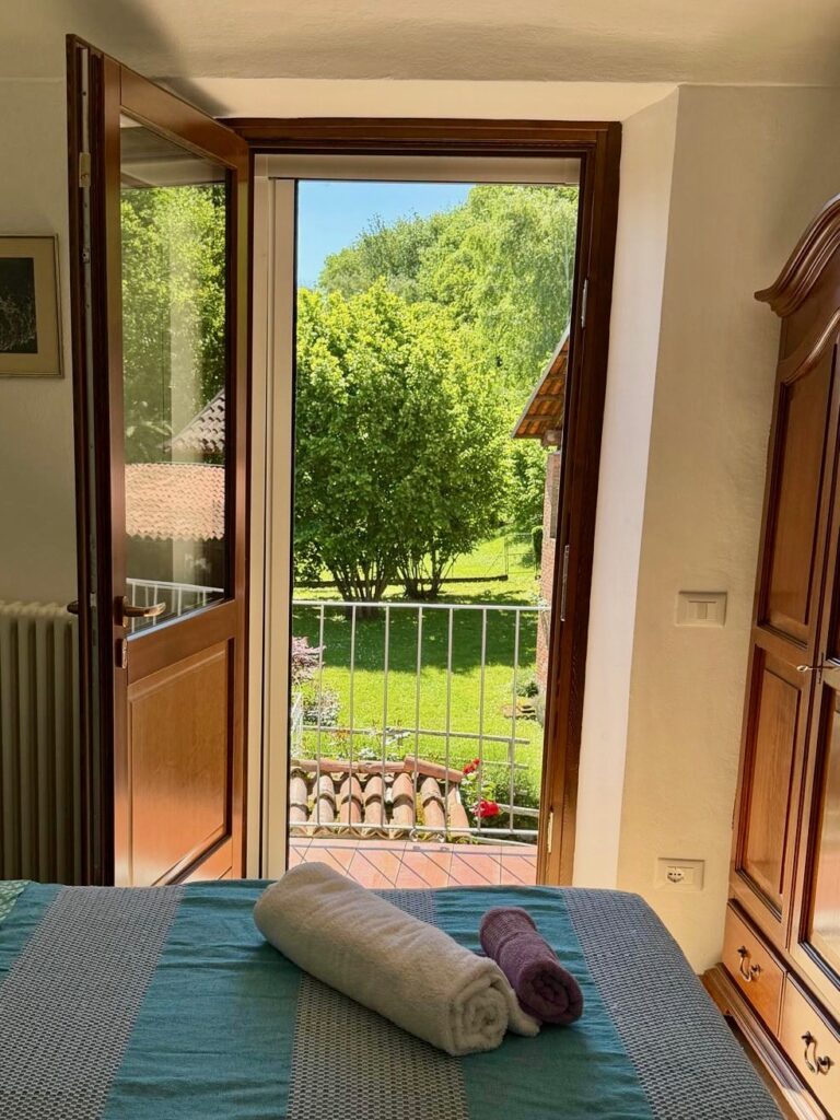 Chambre lumineuse avec lit préparé et balcon ouvert sur jardin verdoyant