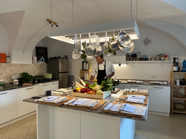Chef préparant des légumes frais sur un îlot central dans une cuisine lumineuse
