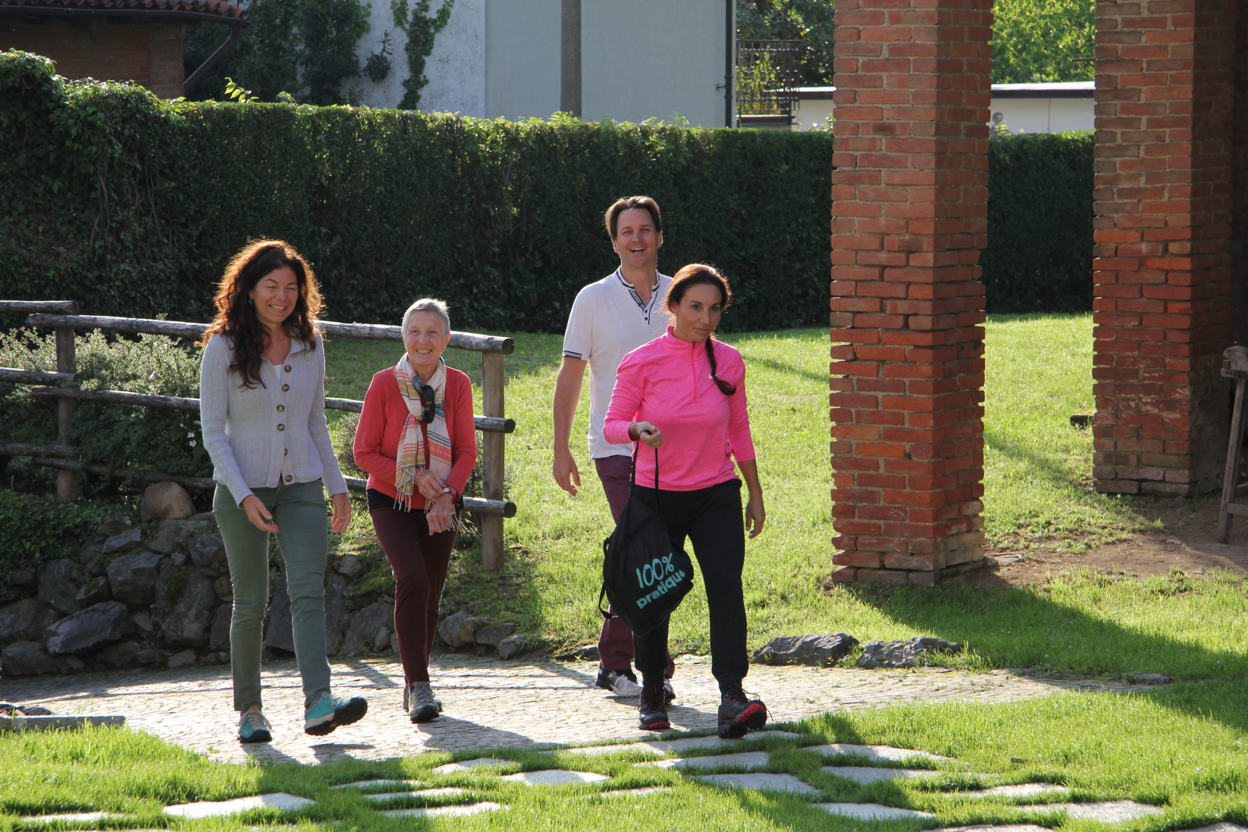 Groupe d’amis en promenade dans un jardin ensoleillé avec petit chien