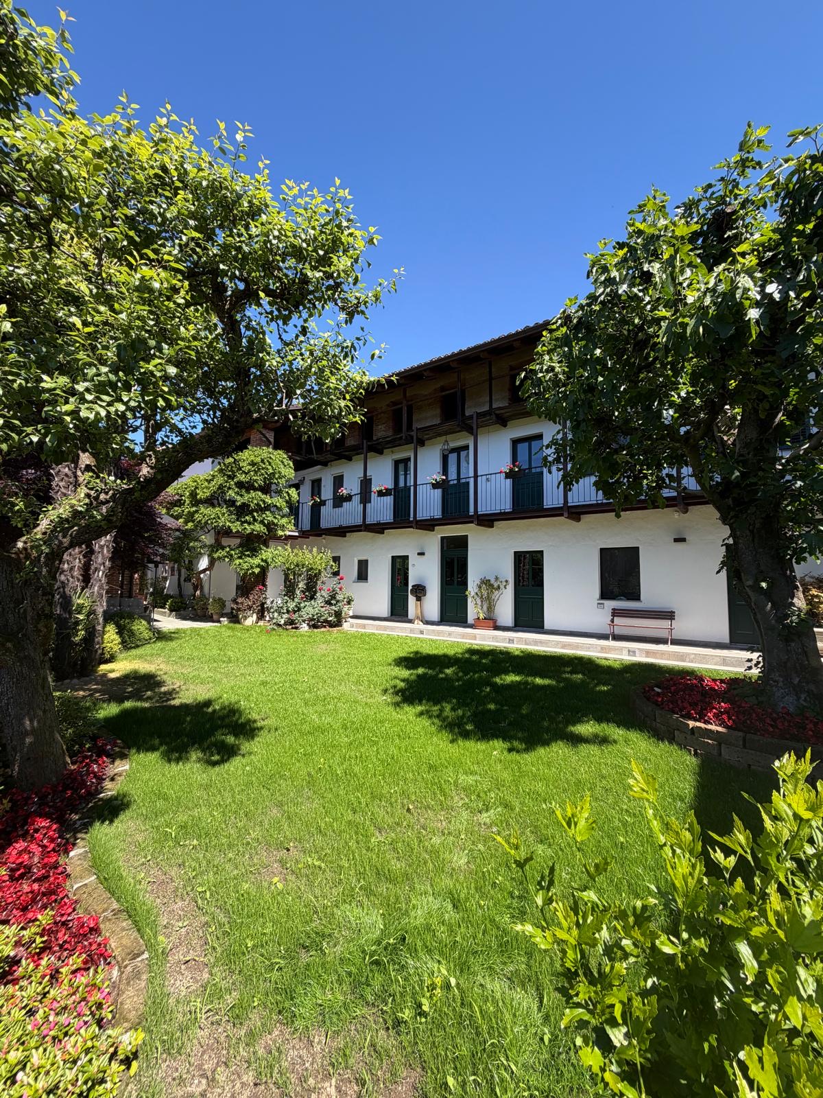 Maison de campagne à façade blanche, balcon en bois et jardin arboré