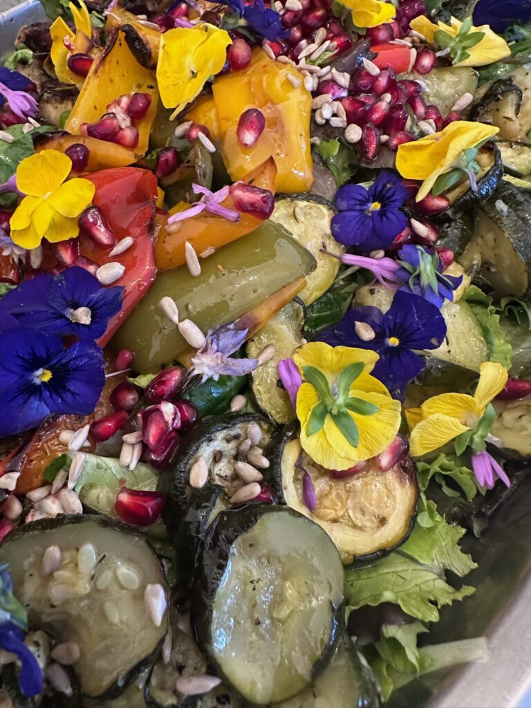 Salade d’aubergine grillée, grenade, courge rôtie et fleurs comestibles