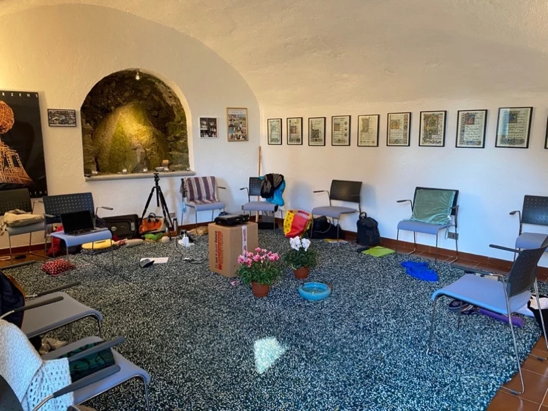 Salle d’atelier chaleureuse avec chaises en cercle, tapis, coussins et plantes