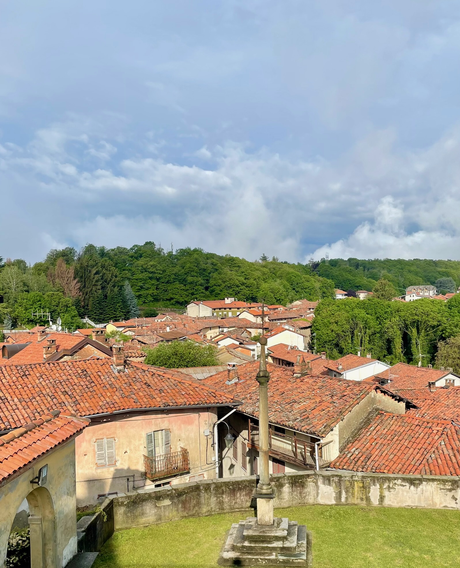 Cour ancienne avec croix en pierre surplombant les toits rouges d’un village historique